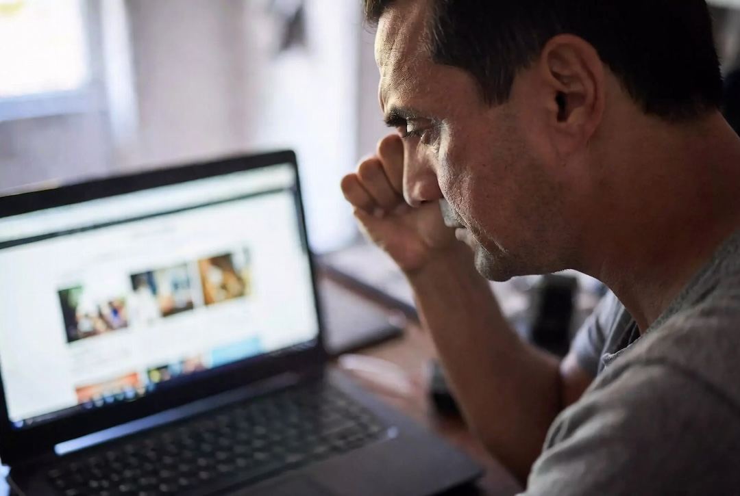 A worried business owner frowning at their outdated website on a laptop