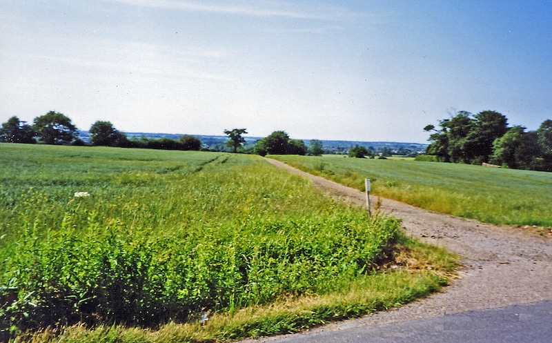The site of the former Inworth station in 2003 — now an open green field with a faint track across it, no sign a railway was ever here