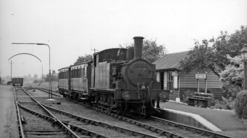 A steam train of the Kelvedon and Tollesbury Light Railway standing at Tiptree station in 1950, with two old carriages and the wooden station building